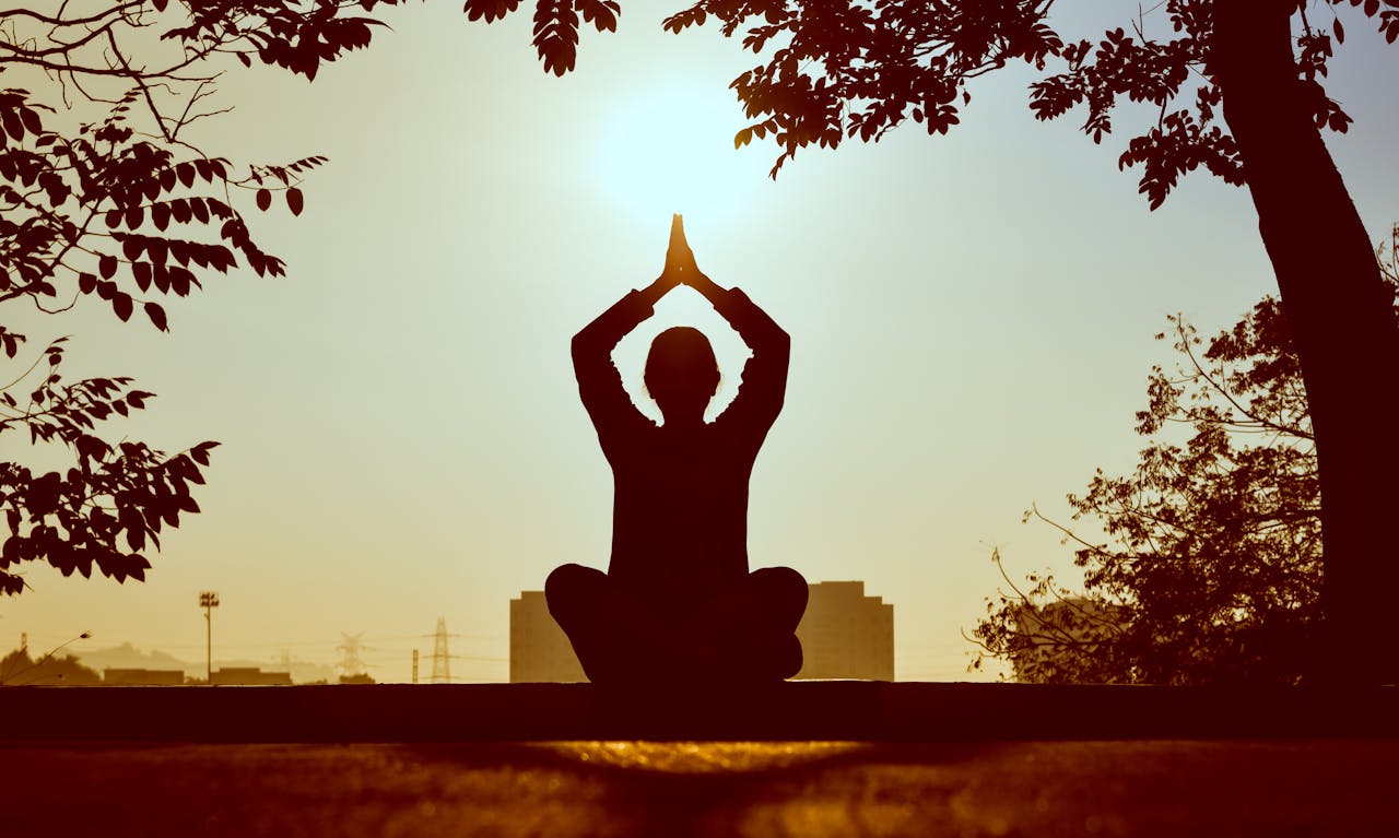 discover Silhouette of a person practicing yoga outdoors during sunrise, creating a calming atmosphere.
